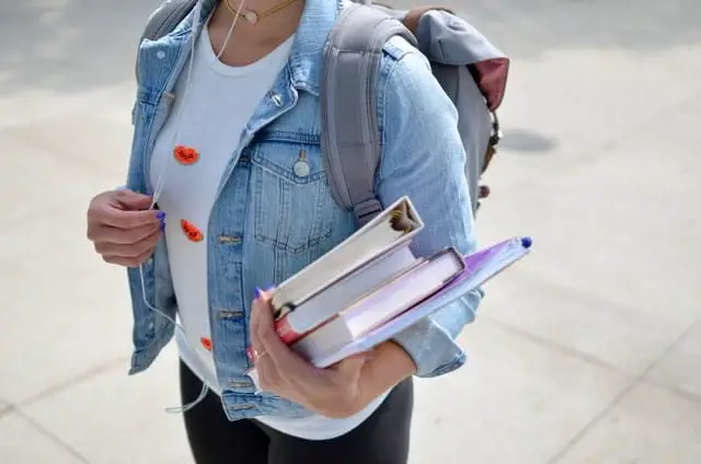 A woman student wearing backpack and holding her books 